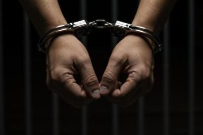 handcuffs-on-wrists-against-dark-background-crime-and-justice-concept-photo.jpg
